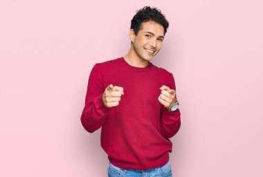 Gündelik giysiler giymiş genç yakışıklı adam mutlu ve komik yüzüyle kamerayı işaret ediyor. iyi enerji ve titreşimler. 