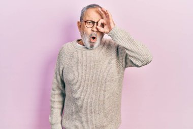 Sakallı, sıradan süveter giyen ve gözlük takan yakışıklı bir adam. Şok olmuş, şaşırmış bir yüz ve parmaklarından bakan bir göz. İnançsız ifade. 