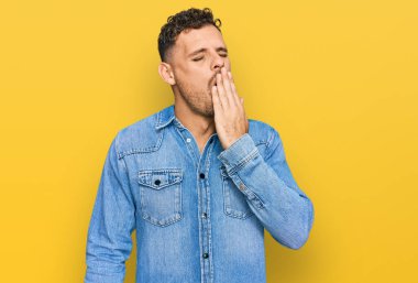 Sıradan bir kot ceket giyen genç İspanyol adam ağzıyla esnemekten sıkılmış. Huzursuz ve uykulu.. 