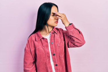 Burun piercingli güzel bir İspanyol kadın. Günlük pembe ceket giyiyor. Burnu ve gözleri ovuşturup yorgun ve baş ağrısı çekiyor. Stres ve hüsran kavramı. 