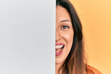 Güzel İspanyol kadın boş pankart tutuyor. Yüzünün yarısını kapatıyor. Çılgınlığı kutluyor ve başarı için hayrete düşüyor.. 