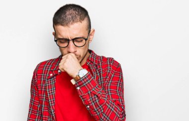 Günlük kıyafetler giyen İspanyol genç adam kendini iyi hissetmiyor ve soğuk algınlığı veya bronşitin belirtisi olarak öksürüyor. sağlık hizmeti kavramı. 