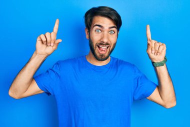 Gündelik kıyafetler giyen genç İspanyol adam şaşırmış, şaşırmış ve parmaklarıyla işaret ediyor ve kollarını kaldırıyordu.. 