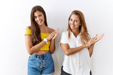 Anne ve kızı, izole edilmiş arka planda birlikte ayakta alkışlıyor ve mutlu ve neşeli bir şekilde alkışlıyor, gururla gülümsüyor. 