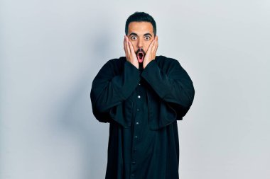 Sakallı yakışıklı, Katolik rahip cübbesi giyen, korkmuş ve şok olmuş, şaşırmış ve şaşırmış bir adam. 