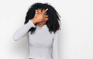 Genç Afro-Amerikan kızı günlük giysiler giyip şok içinde yüzünü ve gözlerini kapayarak utanmış ifadesiyle parmaklarından bakıyor.. 