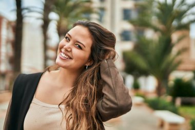 Genç İspanyol kadın gülümseyerek şehirde mutlu mesut dikiliyor..