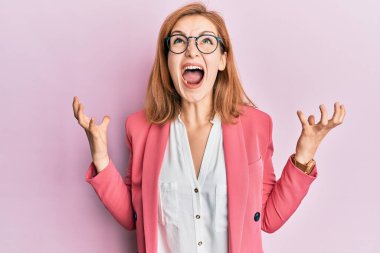 İş stili giyinmiş, gözlüklü, deli deli deli bağıran, agresif ifade ve kollarıyla bağıran beyaz bir kadın. hüsran kavramı. 