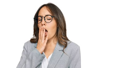 İş elbiseleri giyen genç esmer kadın ağzıyla ağzını kapatmaktan sıkılmış. Huzursuz ve uykulu.. 