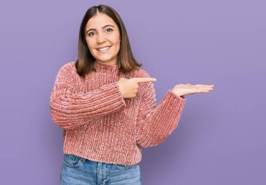 Gündelik giysiler giyen genç ve güzel bir kadın kameraya hayret ediyor ve gülümsüyor.. 
