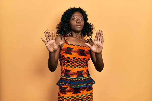 伝統的なアフリカの服を着ている若いアフリカ系アメリカ人女性は 手でジェスチャーを止め ショックを受けて叫びます パニックの概念 — ストック写真