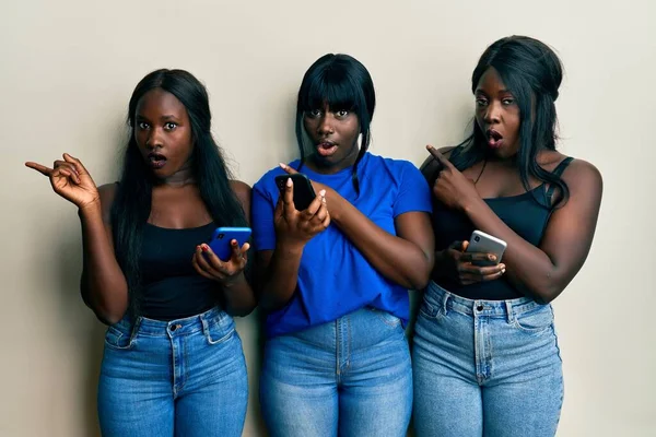 Τρεις Νεαροί Αφροαμερικανοί Φίλοι Που Χρησιμοποιούν Smartphone Έκπληκτοι Δείχνοντας Δάχτυλο — Φωτογραφία Αρχείου