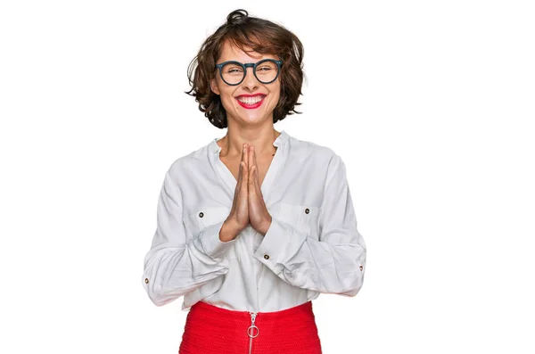 ビジネススタイルを身に着けている若いヒスパニック系の女性と眼鏡を手で祈る一緒に自信を笑顔許しを求めて — ストック写真