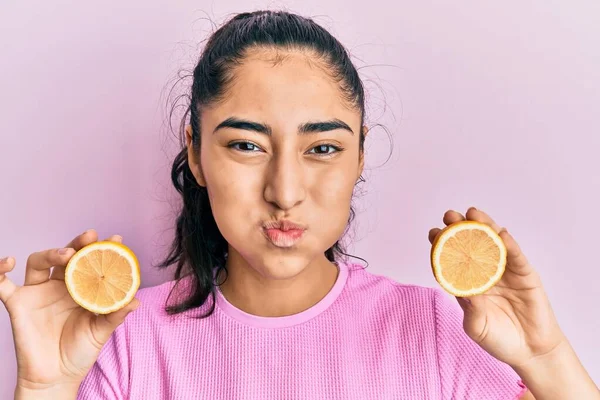 歯のブレースを持つヒスパニック系の10代の女の子は面白い顔でレモンの頬をパフ保持 空気を吸い込み空気を吸い込み — ストック写真
