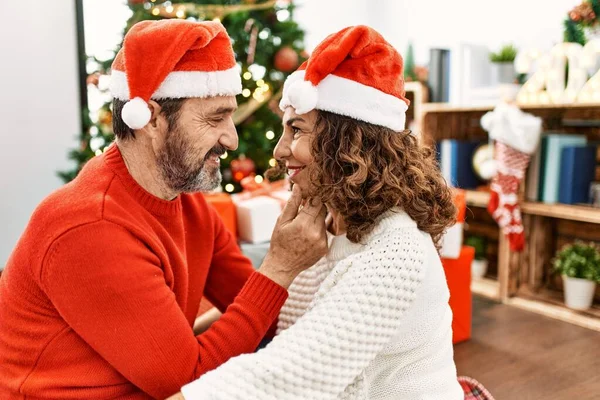Középkorú Spanyol Házaspár Karácsonyi Kalapban Földön Ülve Otthon Ölelkezve — Stock Fotó