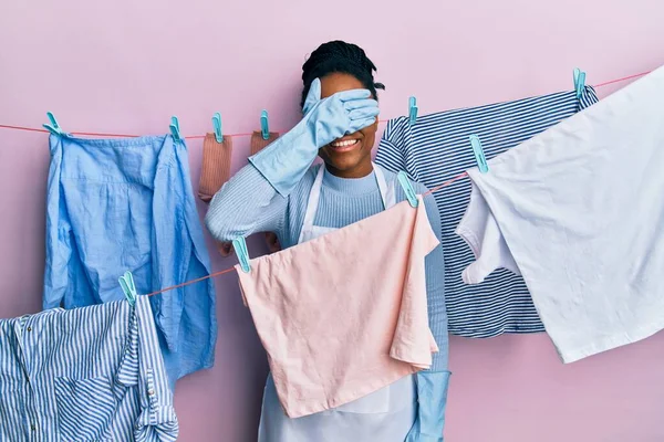 拥有辫子的非裔美国女人在晾衣绳边洗衣服 面带微笑 满脸笑容 惊讶极了 盲目概念 — 图库照片