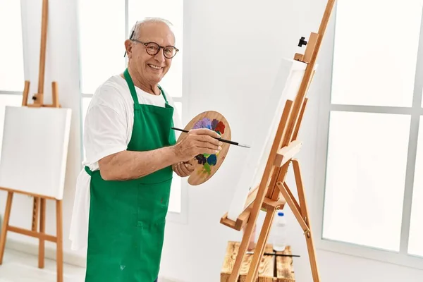 高级灰白头发的画家在艺术工作室里开心地微笑着绘画 — 图库照片
