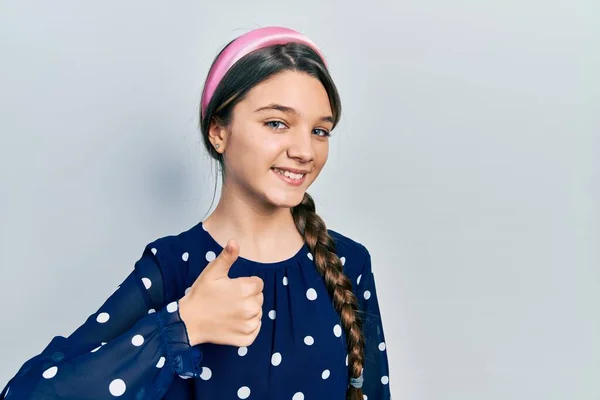 年轻的黑发女孩穿着雅致的衣服 用手拿着快乐的大拇指做手势 赞成的表情看着相机显示的成功 — 图库照片
