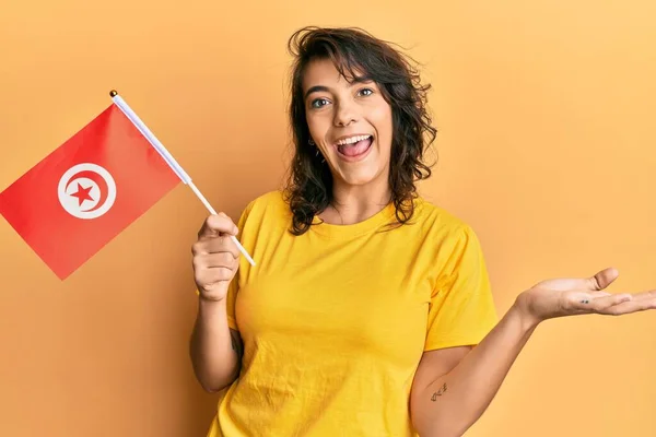 Mujer Hispana Joven Sosteniendo Bandera Tunisia Celebrando Logro Con Sonrisa —  Fotos de Stock