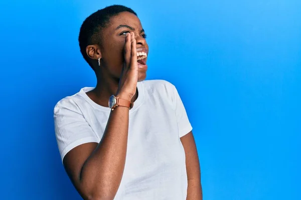 若いアフリカ系アメリカ人の女性は カジュアルな白いTシャツを着て大声で叫び 口の上に手で横に叫んでいます コミュニケーションの概念 — ストック写真