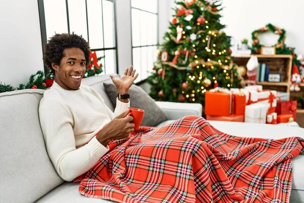 Joven Hombre Afroamericano Sentado Sofá Bebiendo Café Por Árbol Navidad — Foto de Stock