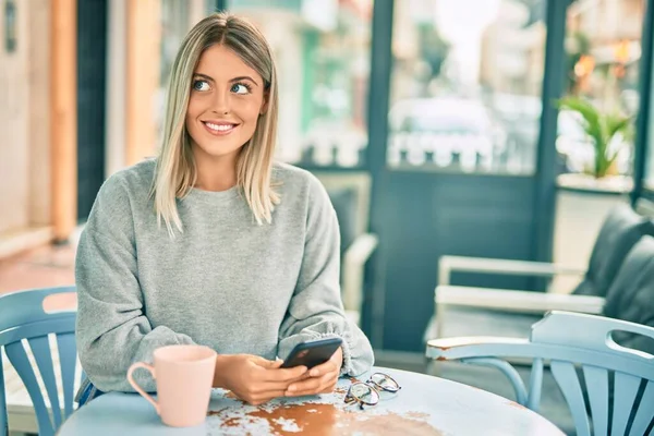 若いですブロンド女の子笑顔幸せな使用スマートフォンでコーヒーショップ — ストック写真