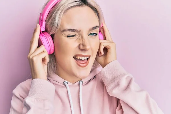 Joven Chica Rubia Escuchando Música Usando Auriculares Guiñando Ojo Mirando — Foto de Stock