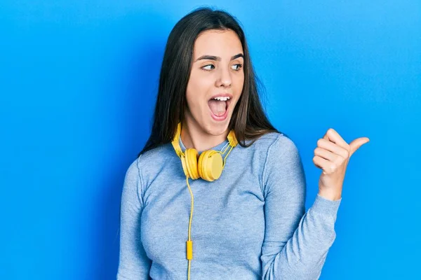 Young Brunette Teenager Wearing Headphones Neck Pointing Thumb Side Smiling — ストック写真