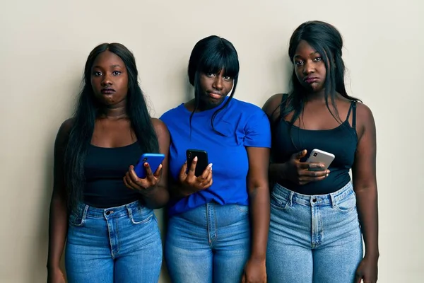スマートフォンを使用して3人の若いアフリカ系アメリカ人の友人が落ち込んで苦痛を心配し 怒って恐れています 悲しい表情 — ストック写真