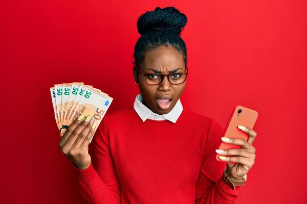 Mladá Africká Americká Žena Používající Smartphone Držící Eurobankovky Šoku Vypadá — Stock fotografie