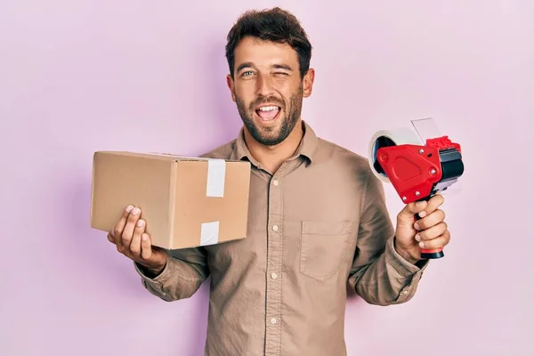 Handsome Man Beard Holding Packing Tape Holding Cardboard Winking Looking — Stock Photo, Image