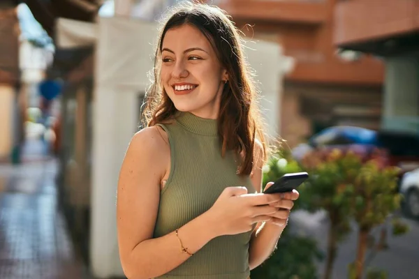 年轻的高加索女孩在城市里用智能手机开心地微笑 — 图库照片