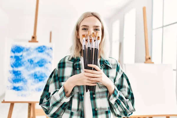 在艺术工作室 年轻的女艺术家高兴地微笑着 手里拿着画笔蒙着脸 — 图库照片