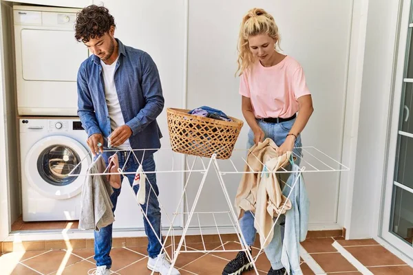 Jovem Casal Sorrindo Feliz Cuidando Roupas Varal Casa — Fotografia de Stock