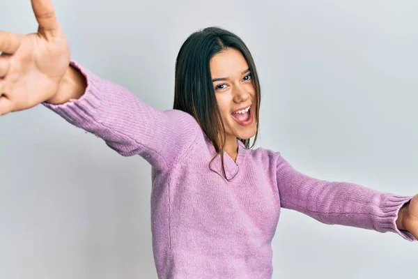 若いヒスパニック系の女の子は抱擁のために腕を開いて笑顔カメラを見てカジュアルな服を着ている 幸せを受け入れる陽気な表情 — ストック写真