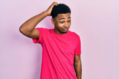 Casua tişörtü giyen Afro-Amerikalı genç bir adam soru sorup kafasını karıştırıyor. Şüpheyle kararsız, kafa kafaya düşünerek. Düşünceli kavram. 