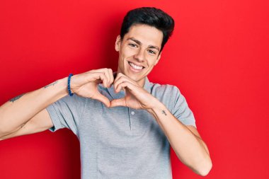 Gündelik kıyafetler giyen, aşık gülümseyen, elleriyle kalp sembolü yapan genç bir İspanyol. romantik kavram. 