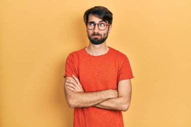 Gündelik kıyafetler ve gözlük takan genç İspanyol adam gülümseyip yan tarafa bakıyor ve düşünüyor.. 