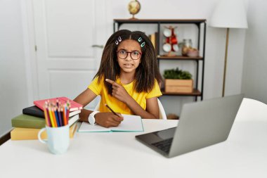 Genç Afro-Amerikan kızı evde ödevini yapıyor. Endişeli ve endişeli bir ifadeye işaret ediyor. 