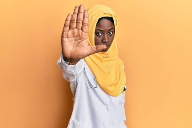 Güzel Afrikalı genç bir kadın doktor üniforması giyiyor ve tesettüre girip, avuç içiyle şarkı söylemeyi kesiyor. Yüzünde olumsuz ve ciddi bir jest olan uyarı ifadesi. 