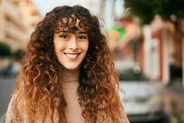 Genç İspanyol kadın gülümseyerek şehirde mutlu mesut dikiliyor.