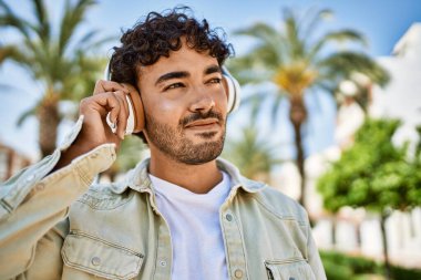 Yakışıklı, sakallı, neşeli, güneşli bir günde kulaklık takan bir İspanyol.
