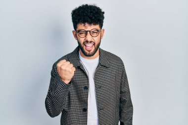 Sakallı, kızgın, kızgın, kızgın yumruğunu kaldıran öfkeli ve öfkeyle bağıran genç bir Arap. öfke ve agresif konsept. 