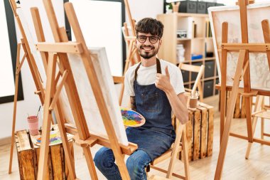 Sanat stüdyosunda sakallı, mutlu ve pozitif gülümseyen, mükemmel ve onay işareti yapan İspanyol bir adam. 