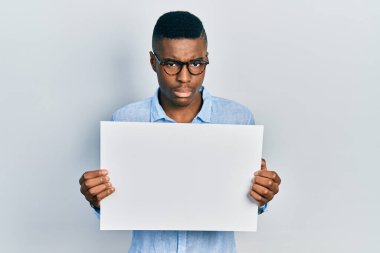 Gözlüklü, boş pankart taşıyan, şüpheci ve gergin, sorun yüzünden surat asan Afrikalı genç bir Amerikalı. negatif kişi. 