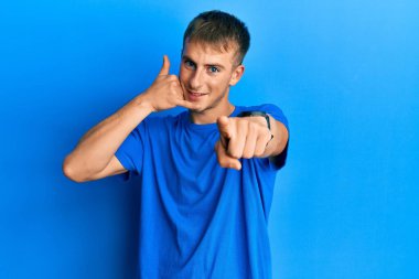 Günlük mavi tişört giyen genç beyaz adam gülümsüyor telefonda konuşuyor ve seni işaret ediyor. Ara beni.. 