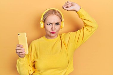 Kulaklık takan, kuşkucu ve gergin genç sarışın bir kadın sorun yüzünden kaşlarını çatıyor. negatif kişi. 