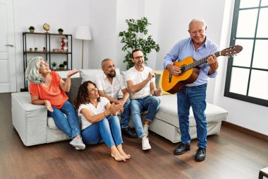 Bir grup orta yaşlı arkadaş evdeki kanepede oturup klasik gitar çalıyorlar..