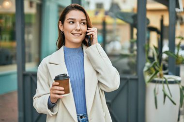 Genç İspanyol kadın akıllı telefondan konuşuyor ve şehirde kahve içiyor..