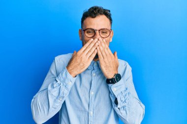 Günlük kıyafetler ve gözlük takan genç İspanyol adam gülüyor ve utanıyor kıkırdıyor ağzı ellerle, dedikoduyla ve skandal konseptiyle örtüyor. 